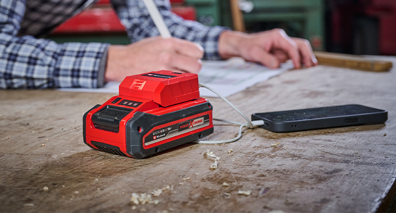 someone using a Power X-Change battery with USB adapter as a powerbank to charge his smartphone