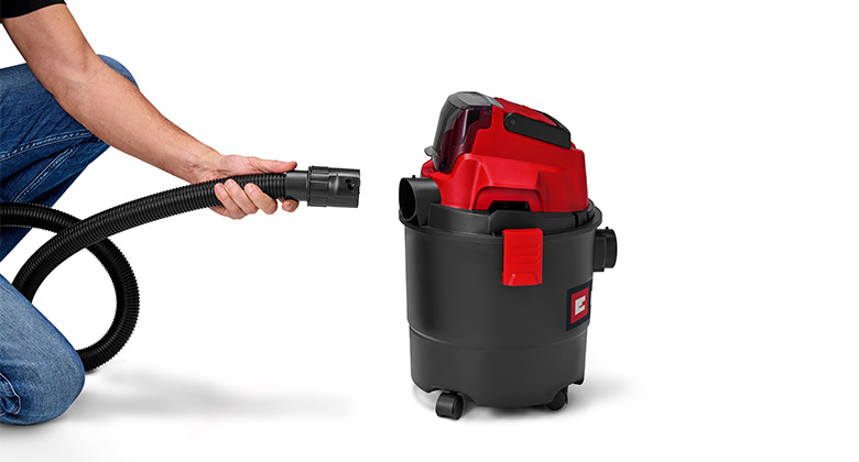 A person demonstrates how to connect the suction hose to an Einhell wet-dry vacuum cleaner.
