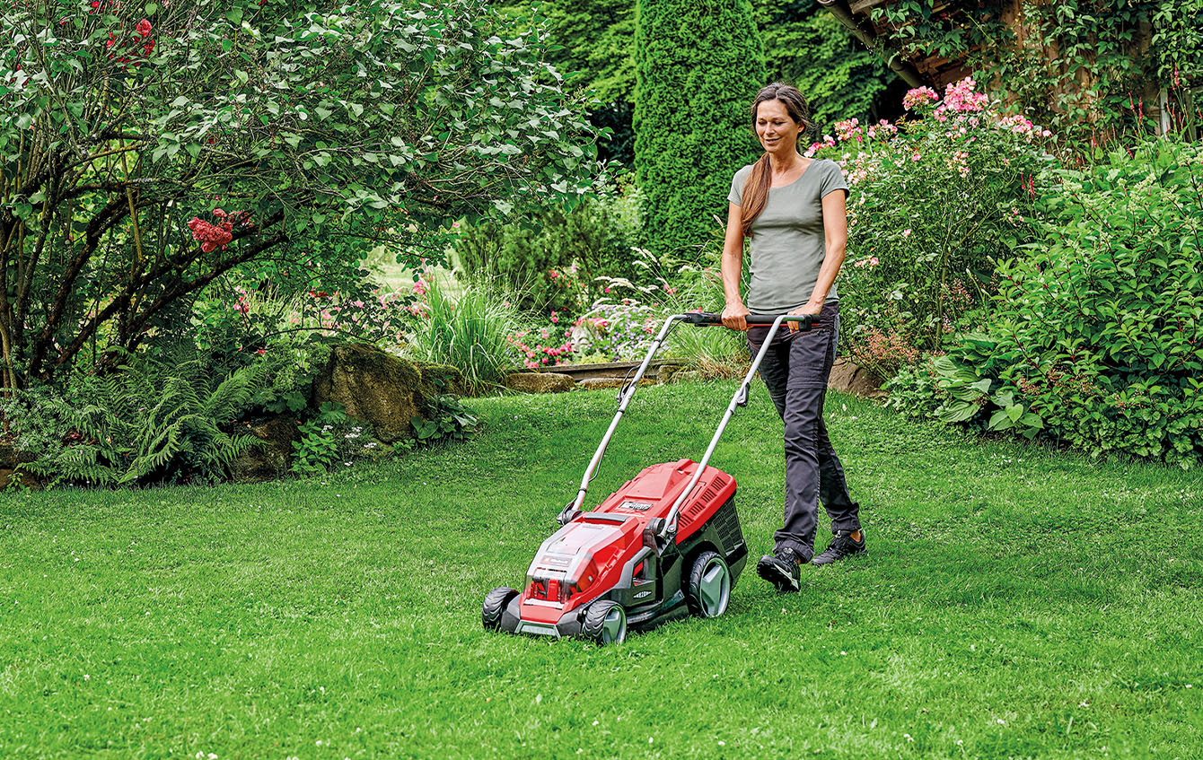 a woman is mowing the lawn with a Einhell cordless lawn mower