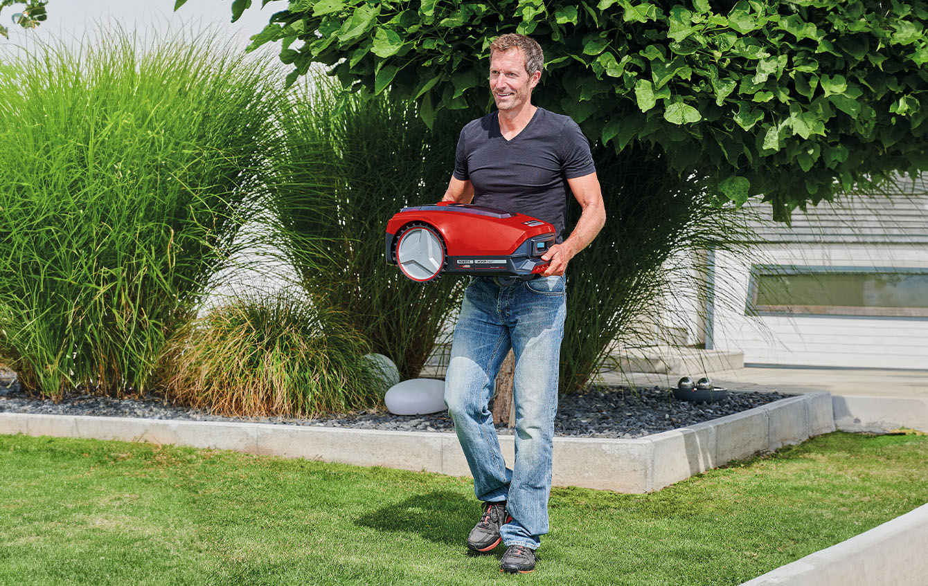 a man carries a Einhell robot mower