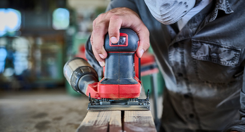 Close-up of an Einhell cordless sander working on a piece of wood.