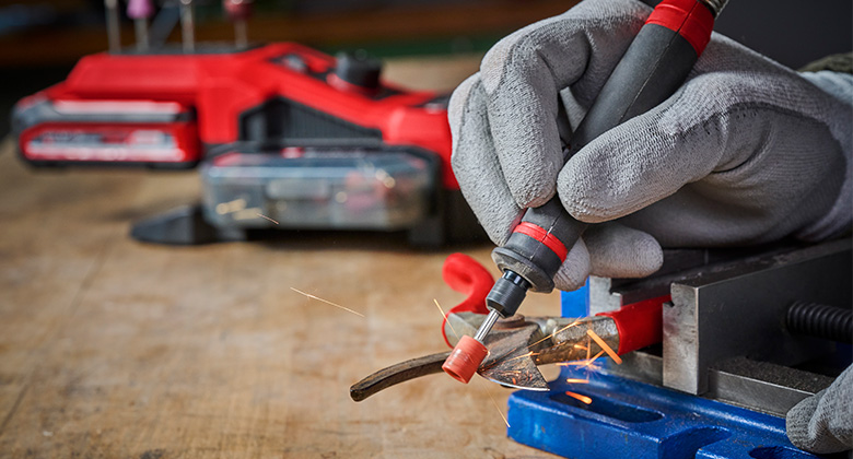 Close-up of an Einhell cordless engraving tool producing sparks while grinding.