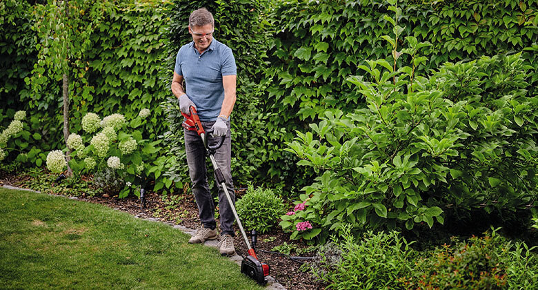 A man trims the edges of his lawn with the Einhell cordless lawn edger.