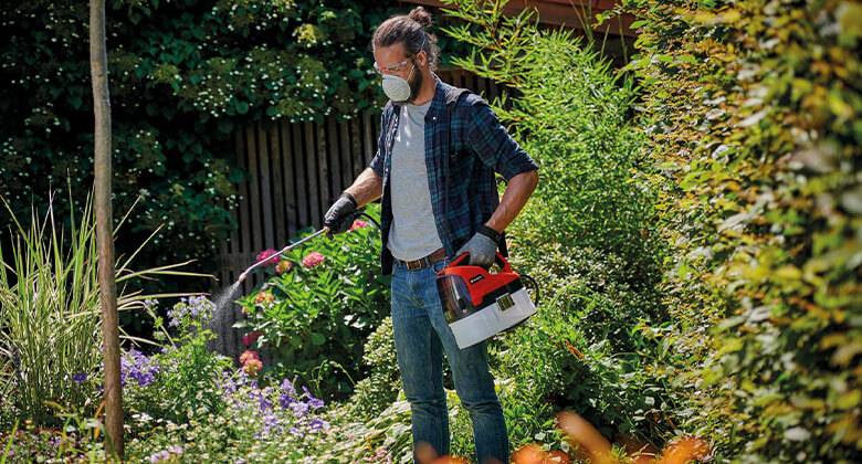 man working with small pressure sprayer in the garden