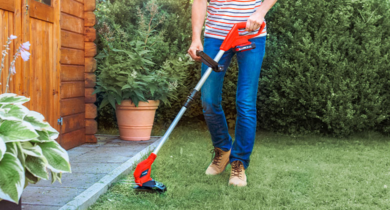 a woman using Einhell Cordless Lawn Trimmer in a garden