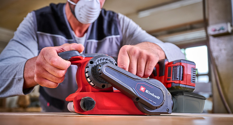 man using cordless band sander