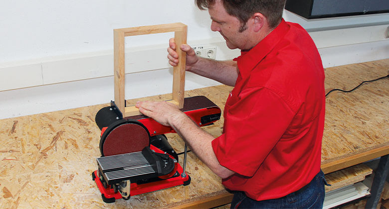 man working with a stationary belt-disc sander